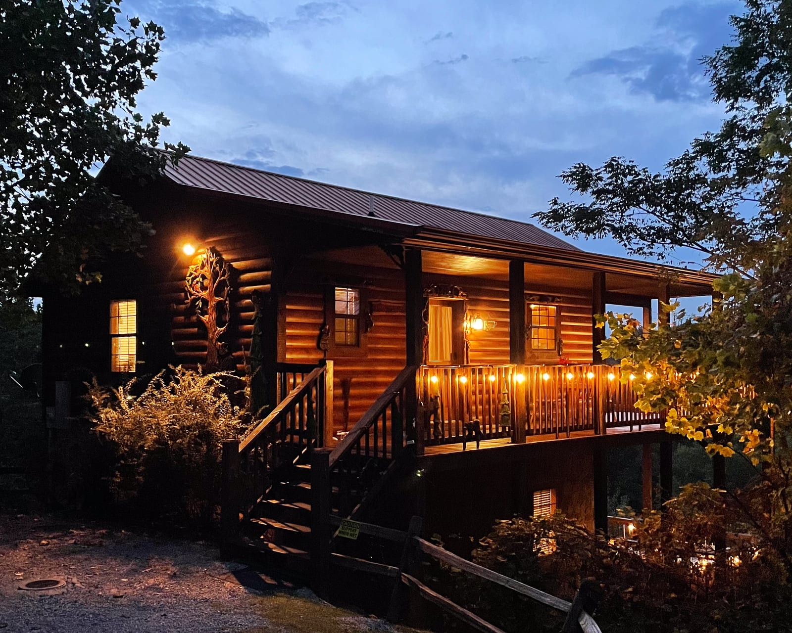 A Smoky Mountain cabin at dusk with the porch lights on, maintained by Lodge Masters