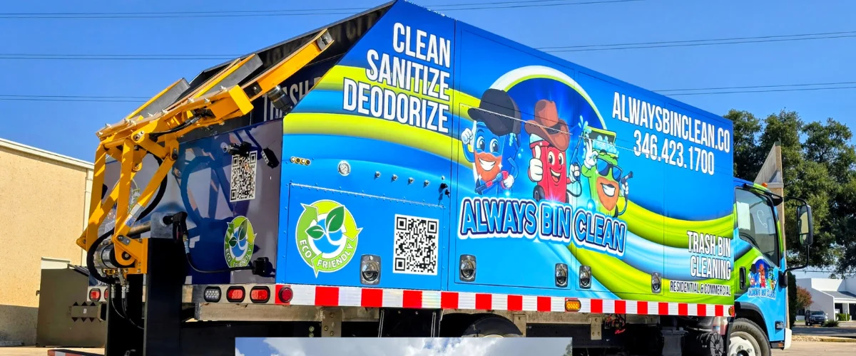 A blue and green "Always Bin Clean" truck with cartoon trash cans on the side, parked outdoors.