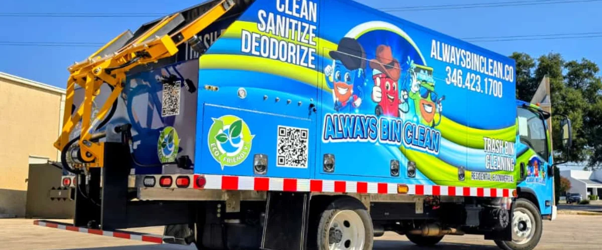 A blue and yellow Always Bin Clean truck, featuring cartoon bins, parked with its back and left side visible.