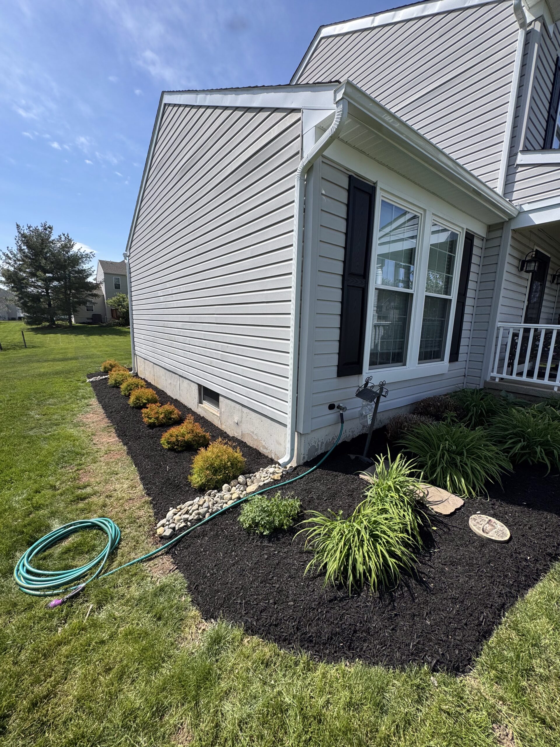 Fresh black mulch beds with ornamental grasses and shrubs along the side of a home in Phoenixville, PA