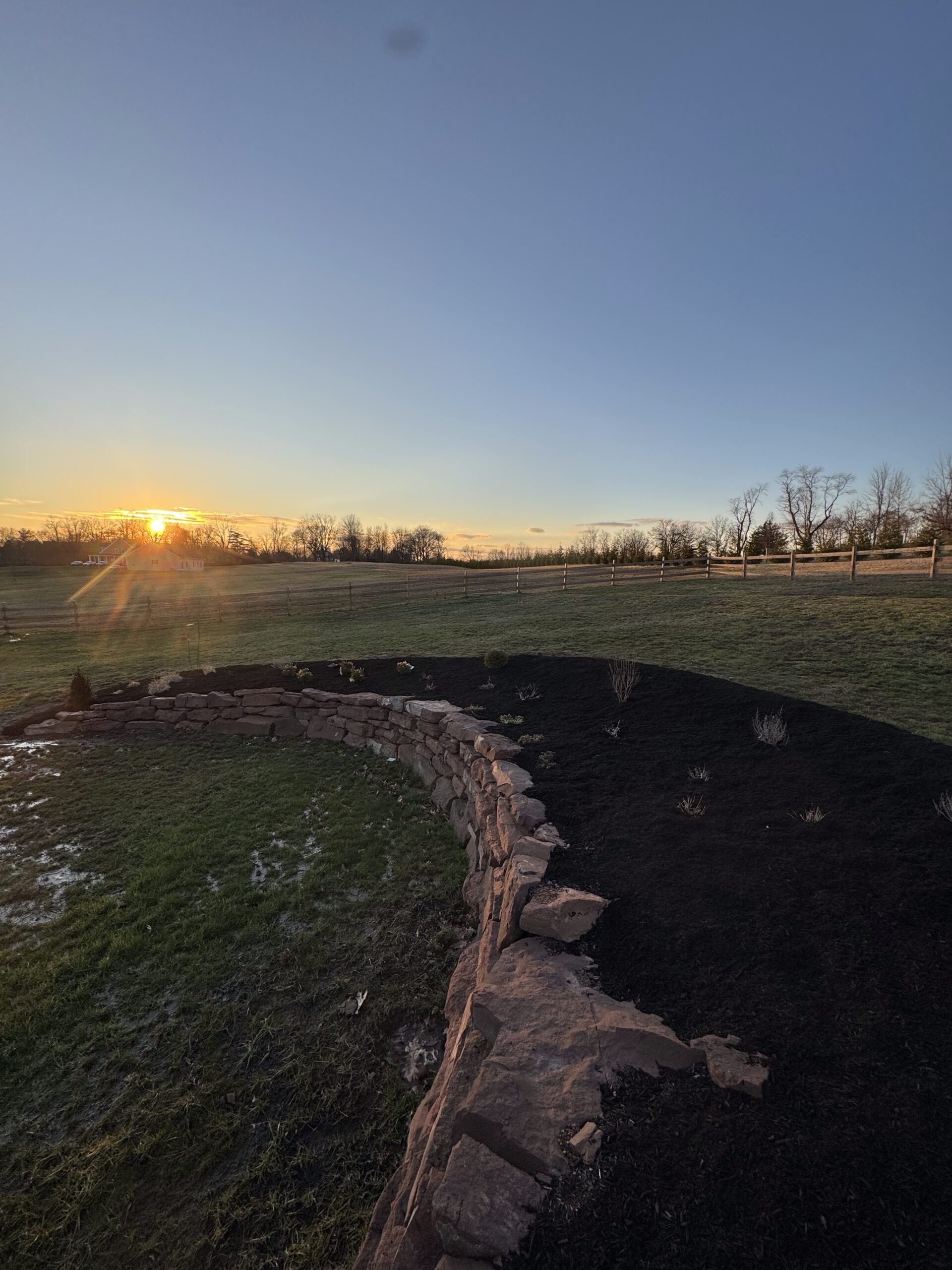 Curved stone retaining wall with fresh mulch built on a residential property near Phoenixville, PA