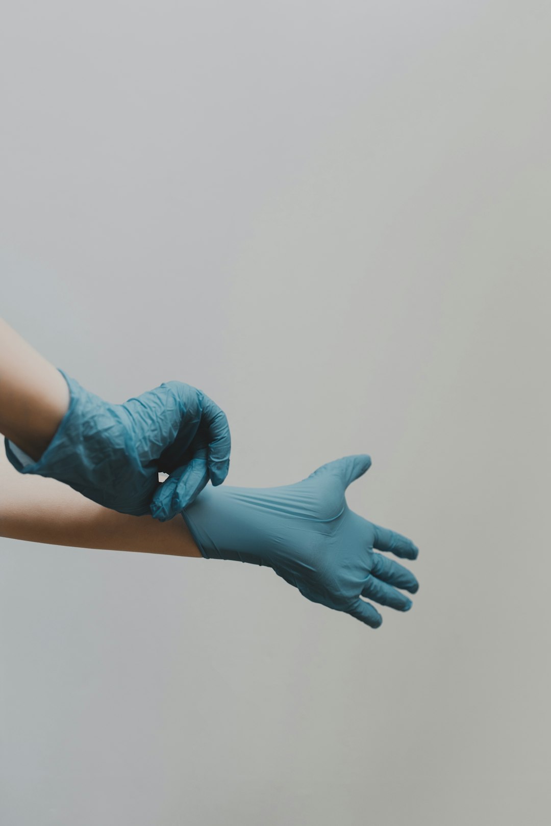 Mains enfilant des gants de nettoyage bleu, symbolisant le professionnalisme et l’hygiène des services B2M à Genève et Vaud