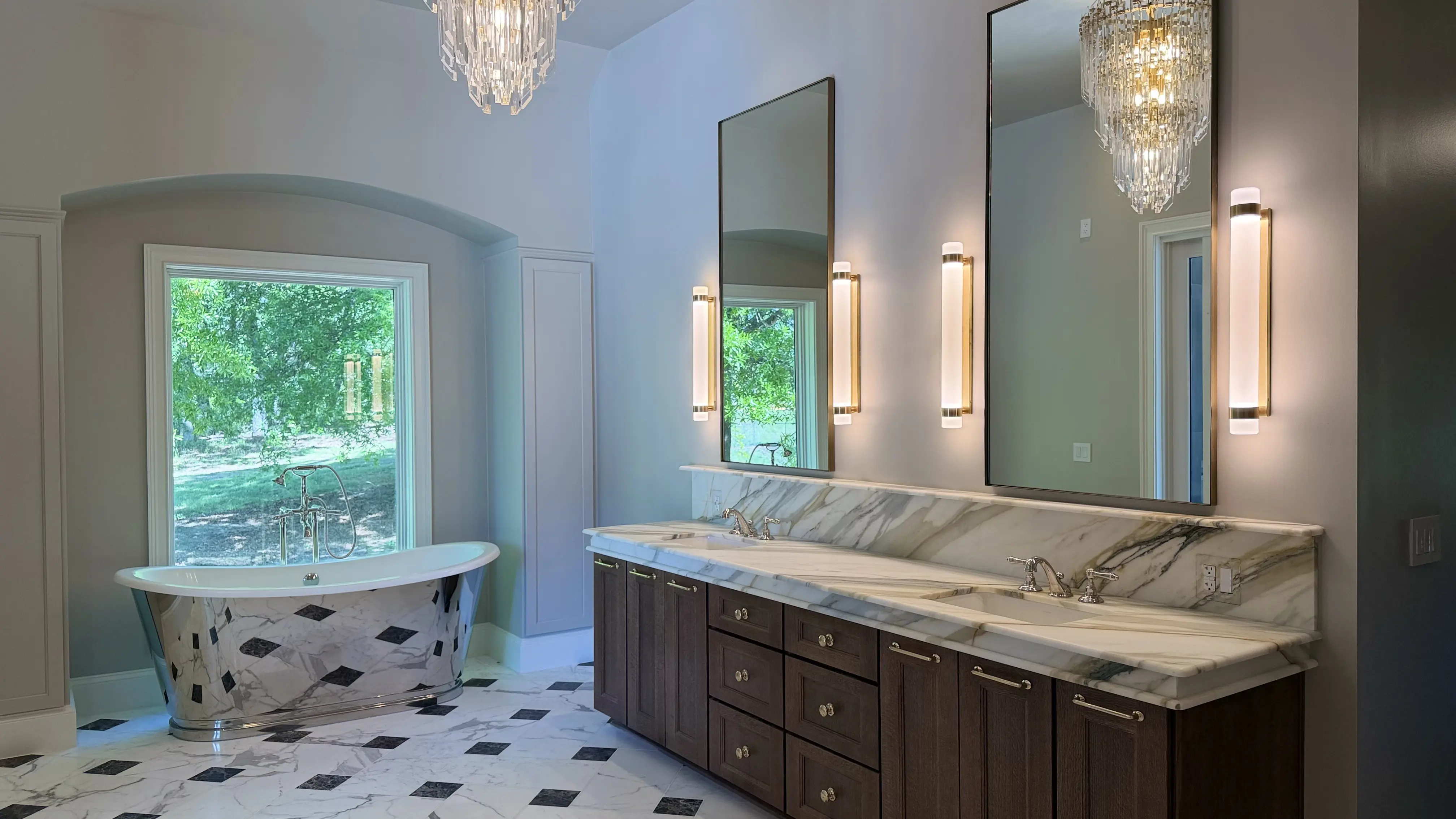 Completed bathroom with a reflective freestanding tub, dark-wood double vanity and stone counters