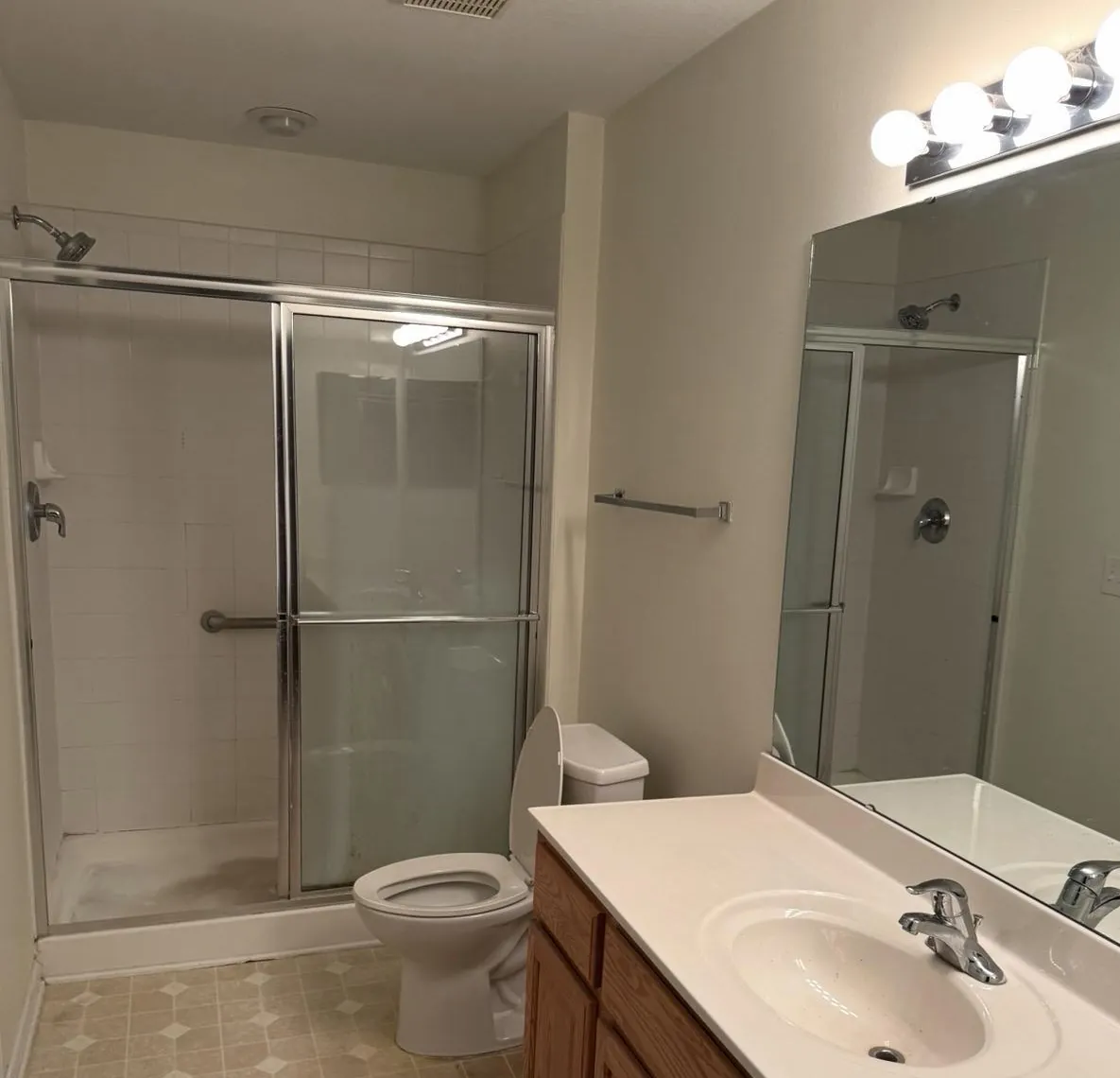 Hall bathroom before the remodel, with a framed sliding shower door and laminate floor