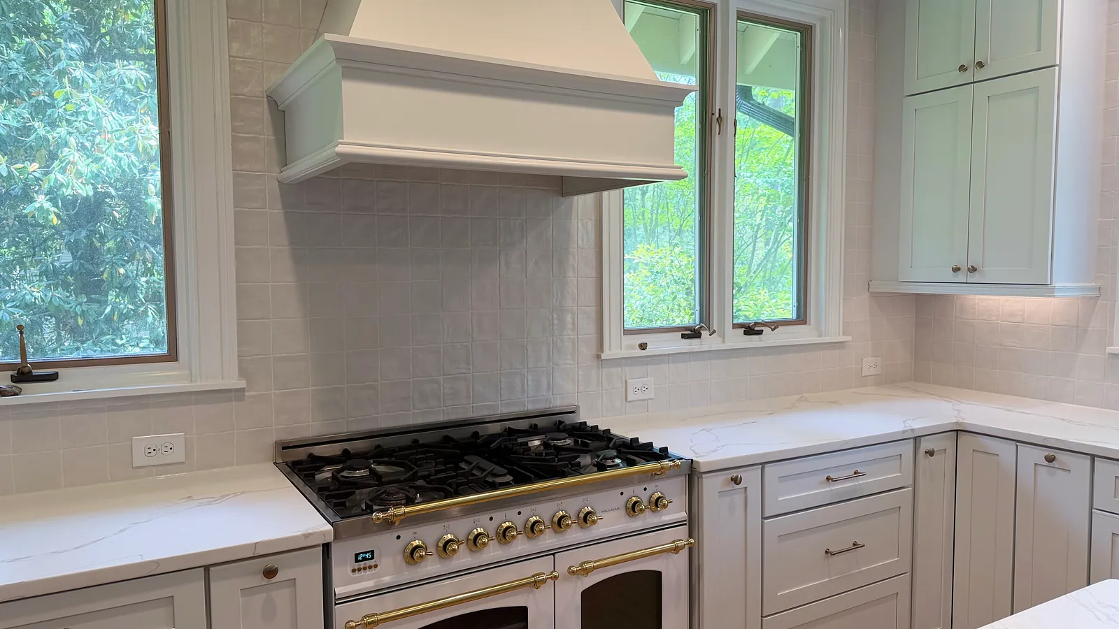 White kitchen with a custom range hood, quartz countertops, and a dual-fuel range