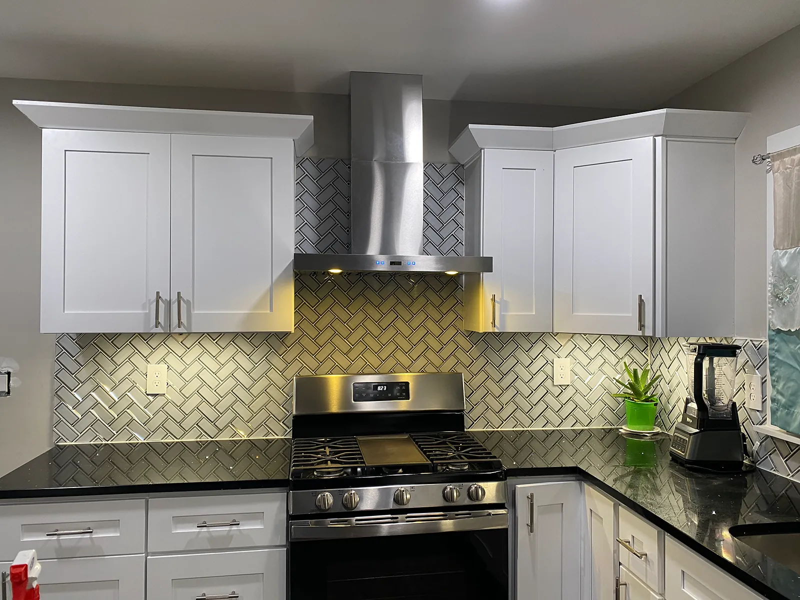 White shaker cabinets with a stainless range hood and herringbone backsplash