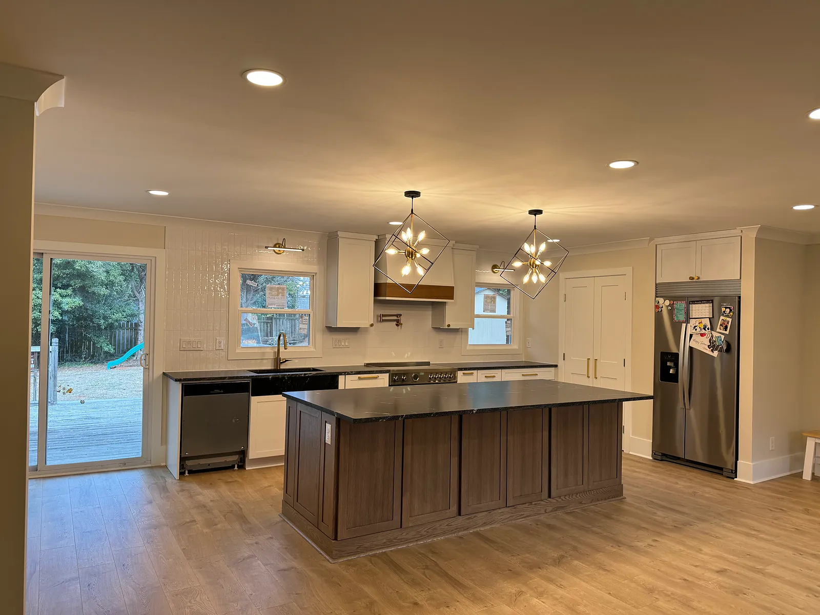 Open-concept kitchen with a large wood island, white cabinets, and pendant lights