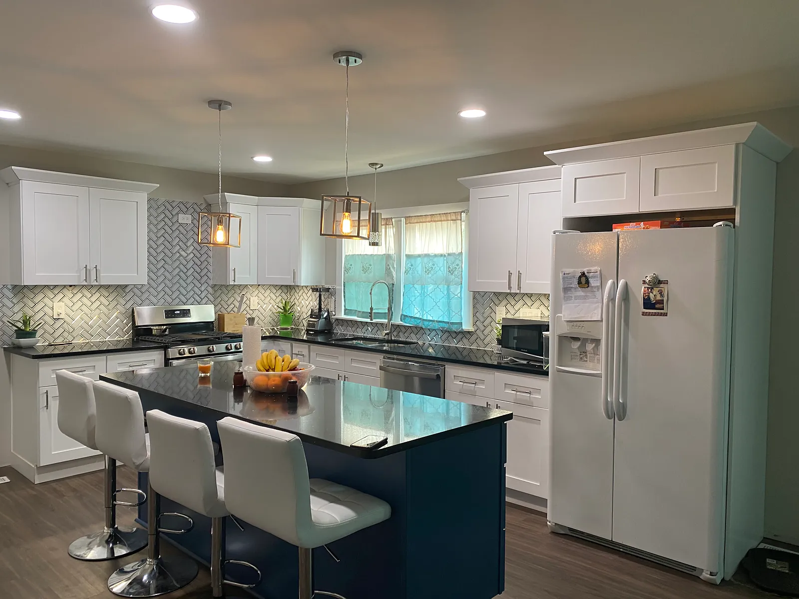 Kitchen with a navy island, white cabinets, and a herringbone tile backsplash