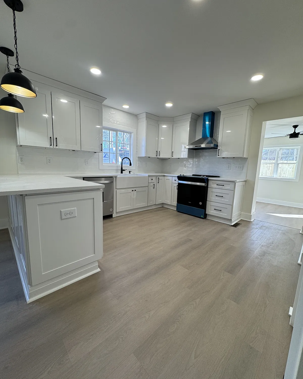 Open-concept kitchen with white cabinets, peninsula seating, and wood-look flooring