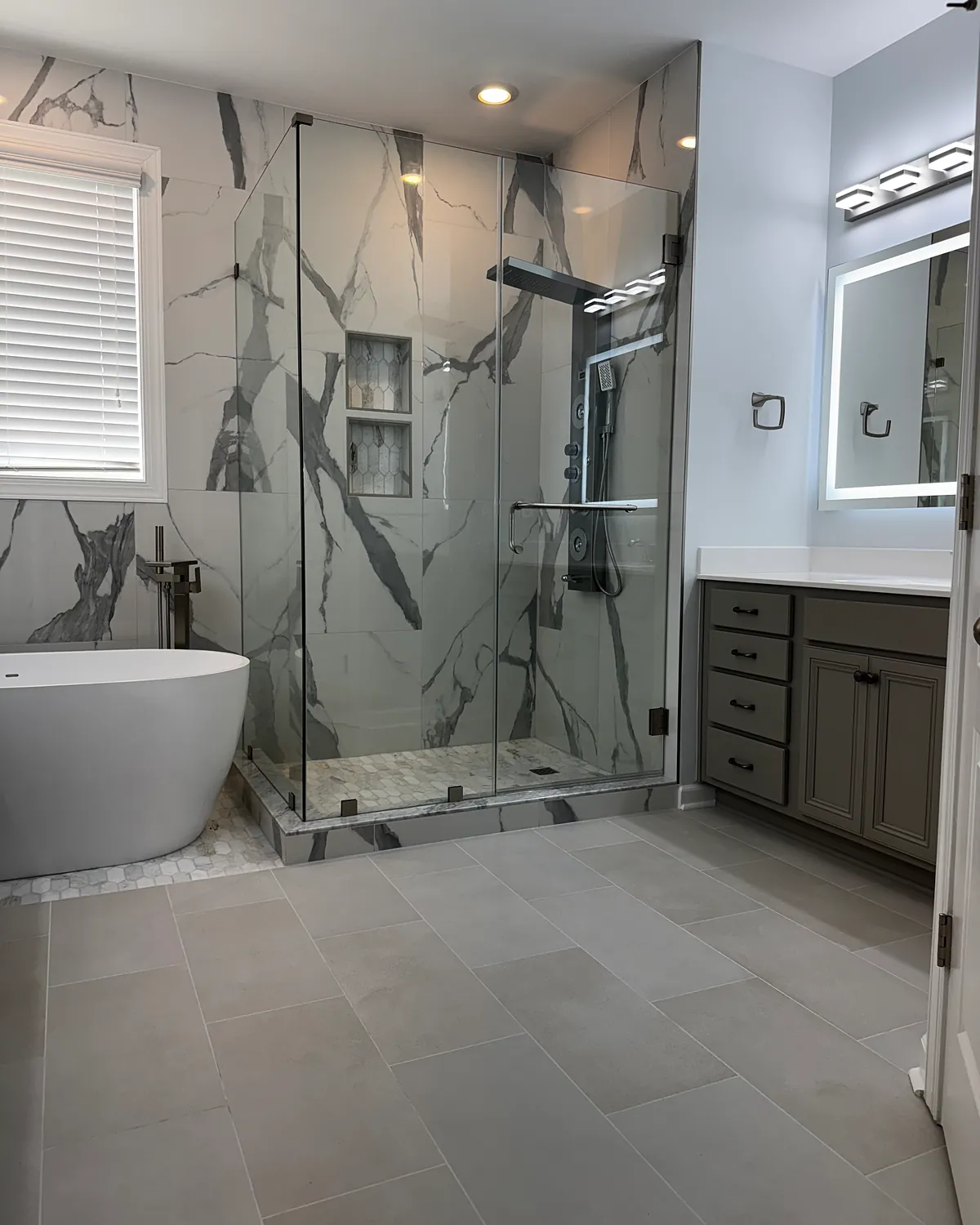 Bathroom with marble-look tile and a glass walk-in shower