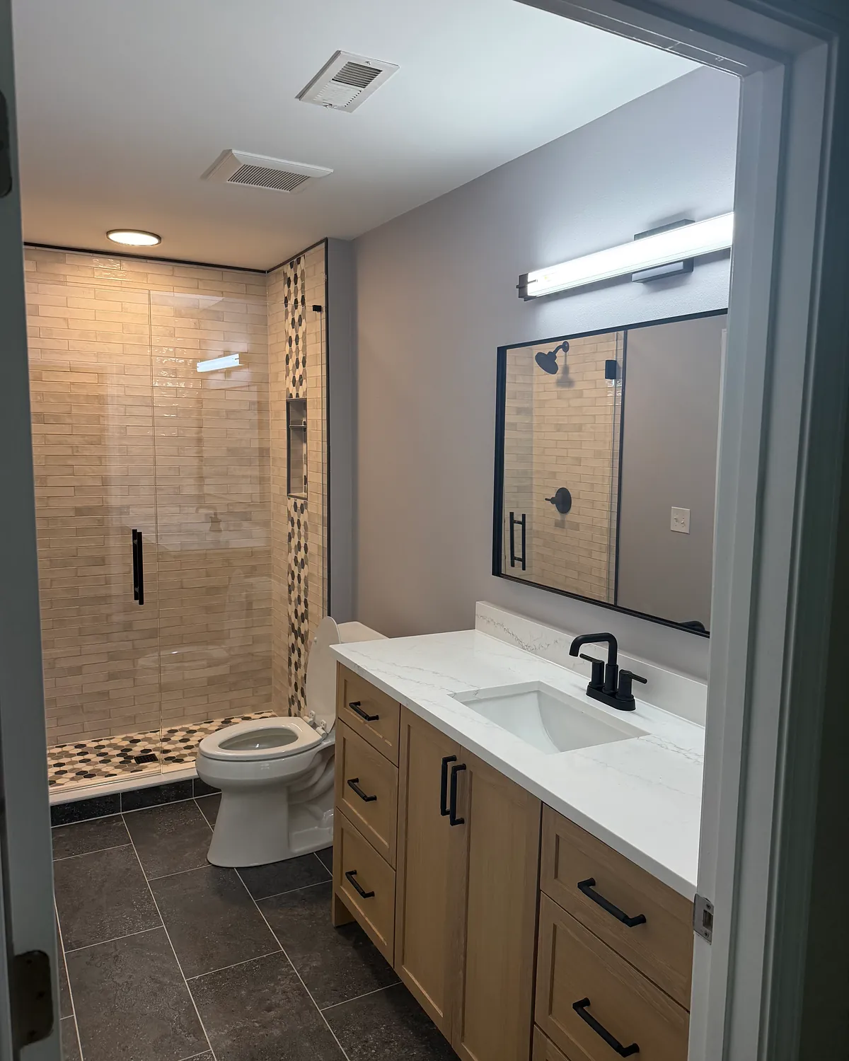 Hall bathroom after remodel with a tiled walk-in shower, black fixtures, and new vanity