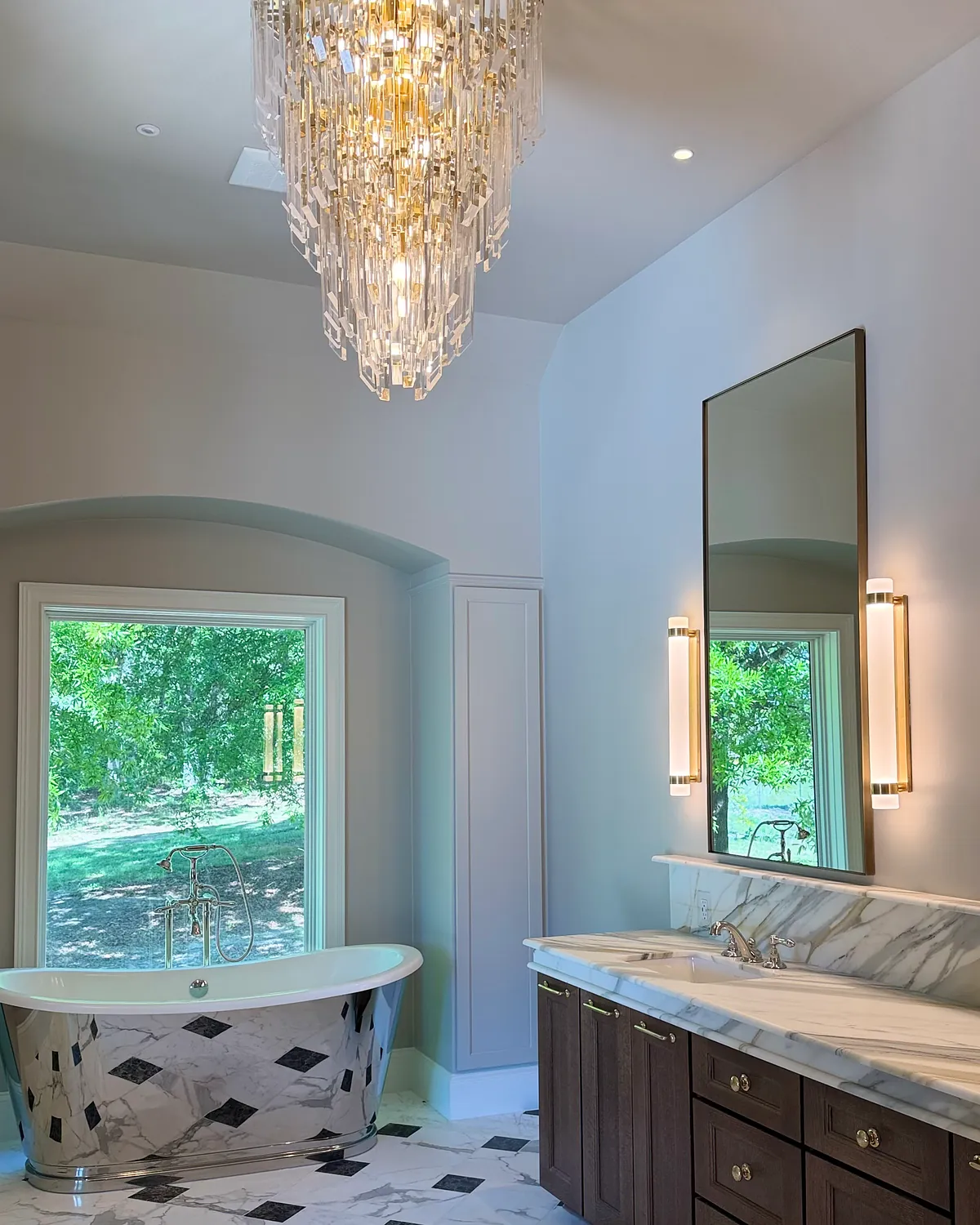 Double vanity with marble countertops beneath a crystal chandelier