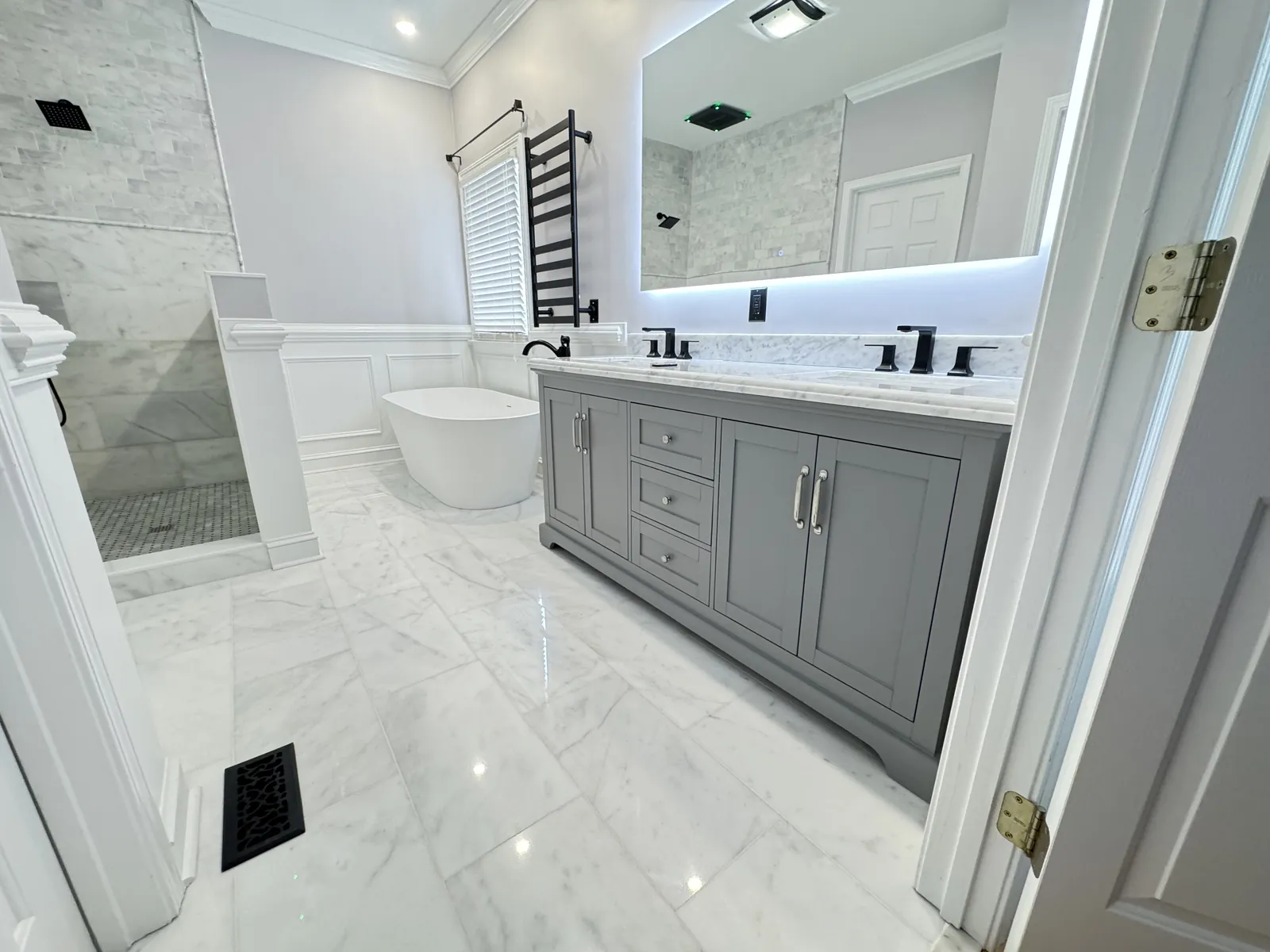 Primary bathroom with marble-look floors and a gray double vanity
