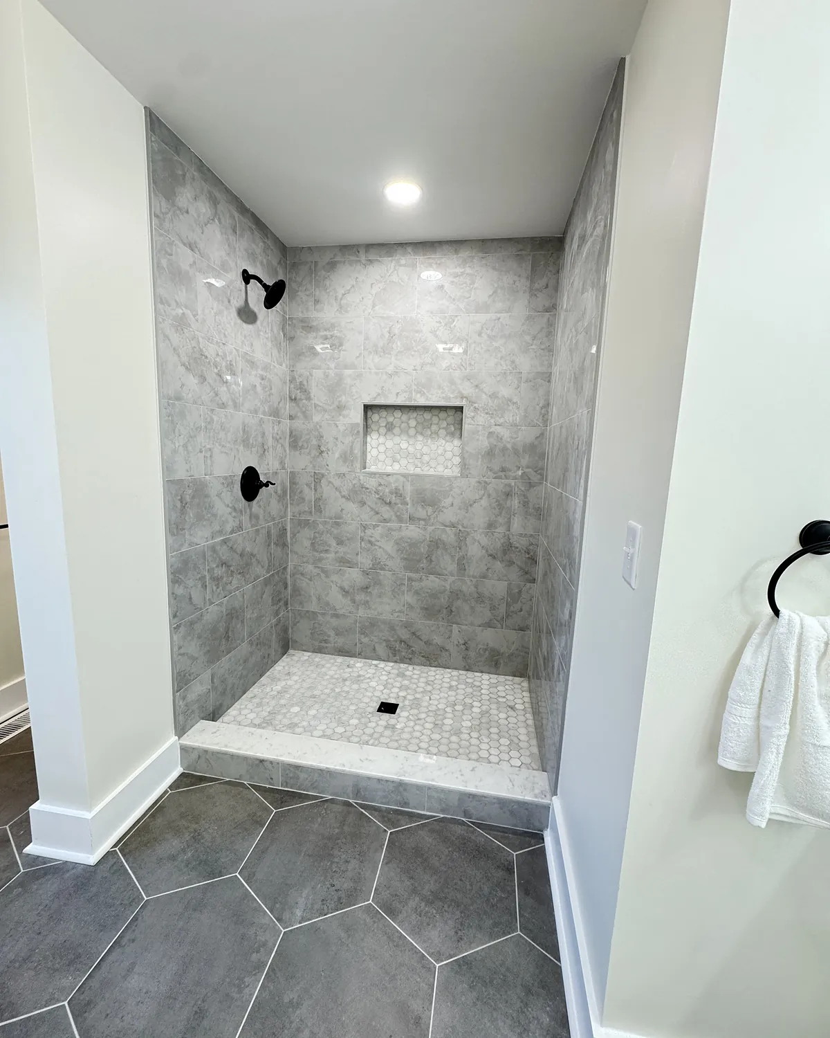 Walk-in shower with hexagon floor tile and black fixtures
