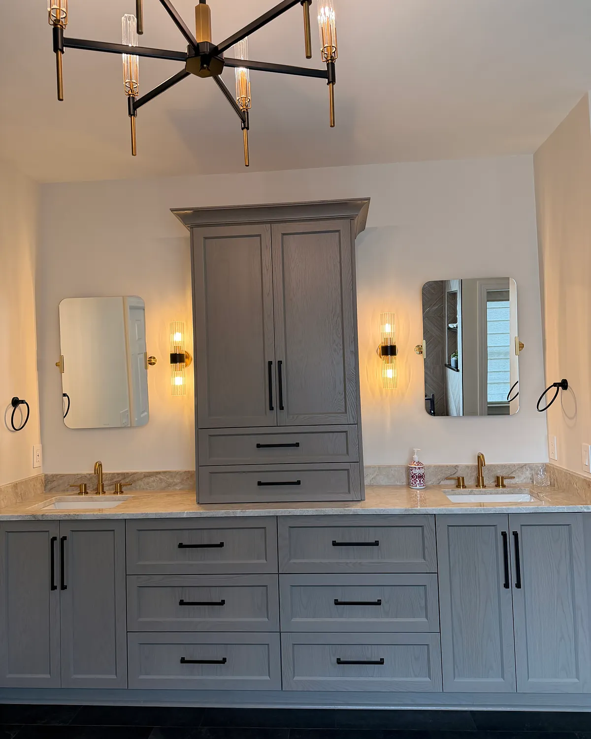 Double vanity with a center linen tower and a chandelier