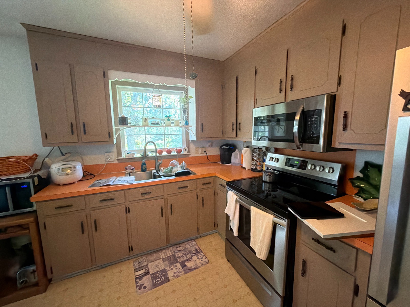 Kitchen before remodeling, with tan cabinets and orange countertops