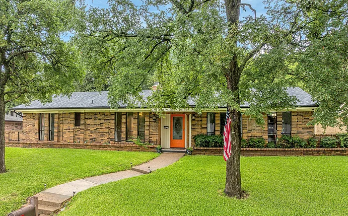 Brick estate home with mature trees and front walkway