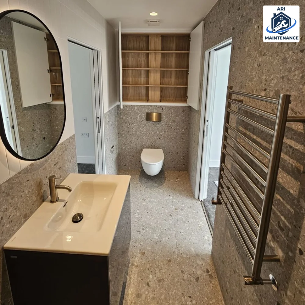 Terrazzo bathroom with oval mirror and sink vanity.