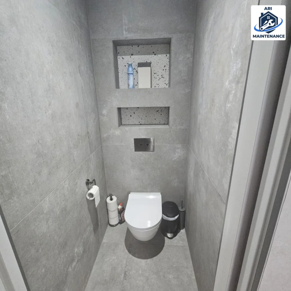Modern WC with grey concrete-effect tile and recessed niche shelves.