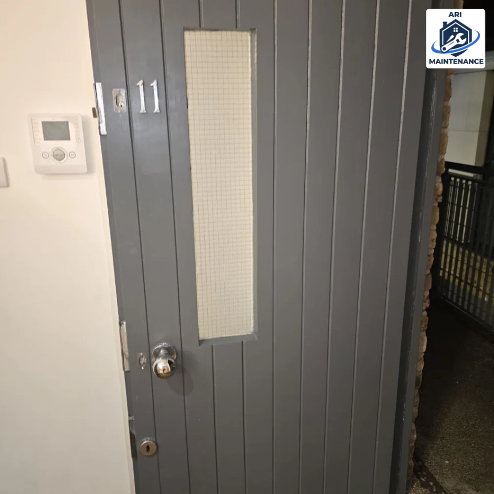 Steel security door close-up showing grey panel and frosted glass insert.