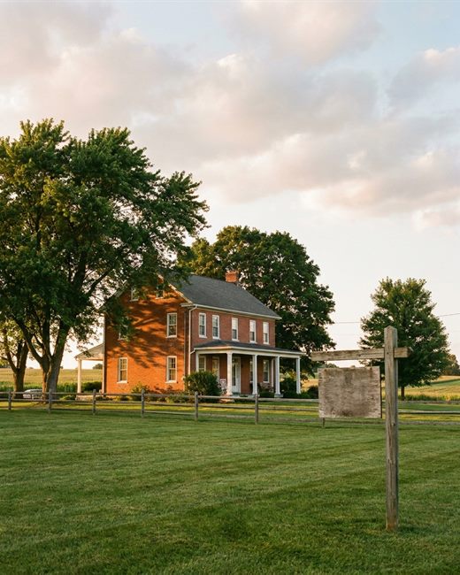 A brick farmhouse home with a white porch at golden hour in Lancaster County