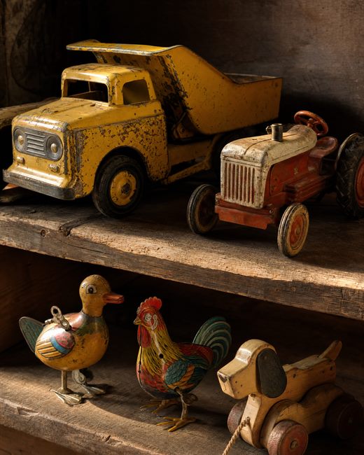 Vintage pressed-steel and cast-iron toys on a plank shelf