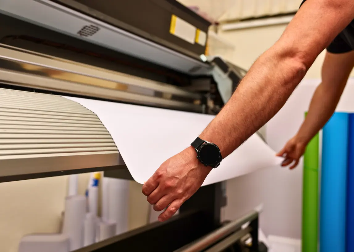 Large format printing in progress at Elite Printing Group, featuring a technician loading material into a wide-format printer for banners, posters, and signage.