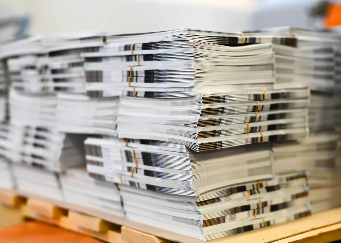Stacks of freshly printed magazines and brochures at Elite Printing Group, showcasing high-quality offset printing and professional finishing services.