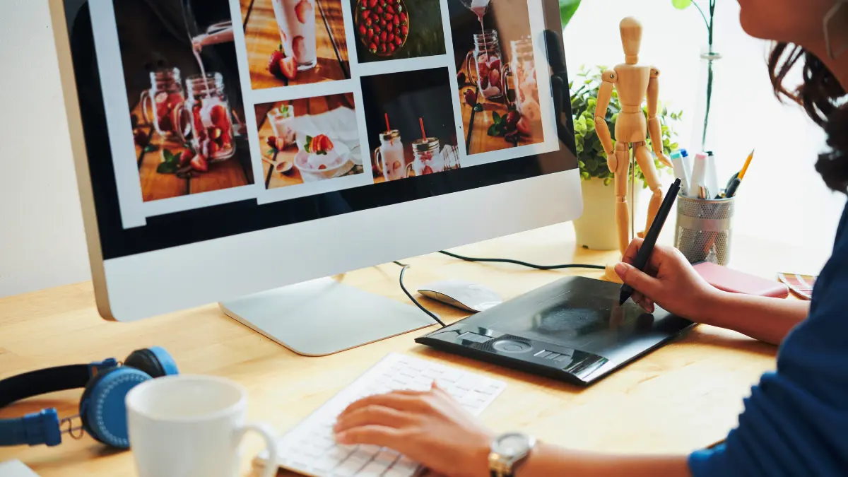 Graphic designer creating visual layouts on a computer using a digital drawing tablet, representing Elite Printing Group’s professional graphic design services.