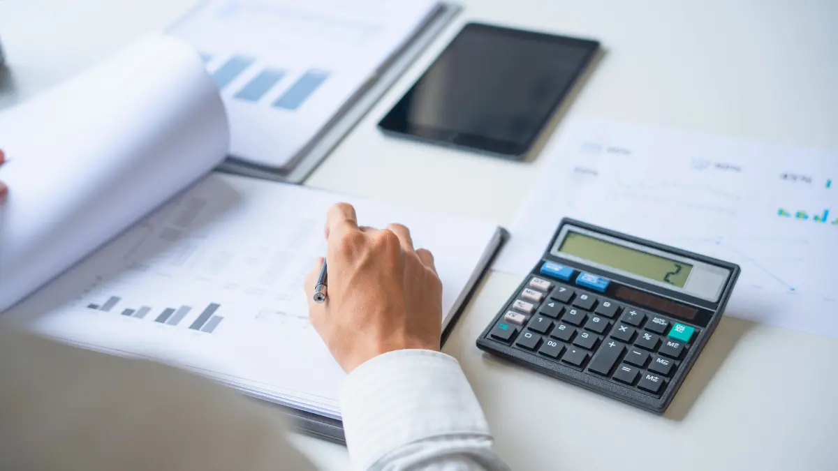 Business person reviewing charts and using a calculator during a print cost analysis for a free print audit at Elite Printing Group.