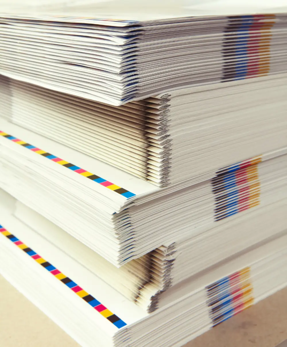 Stack of freshly printed brochures with CMYK color marks from a professional printing press