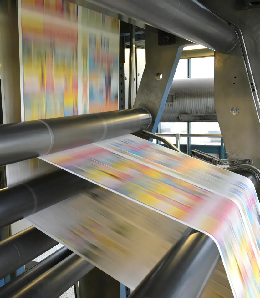 Commercial printing press running full-color sheets through rollers at high speed