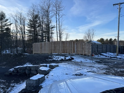 Tall wooden fence surrounding a snow-dusted construction site