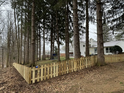 Classic wooden picket fence surrounding a shaded backyard