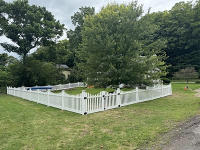 Traditional white picket fence surrounding a landscaped front yard