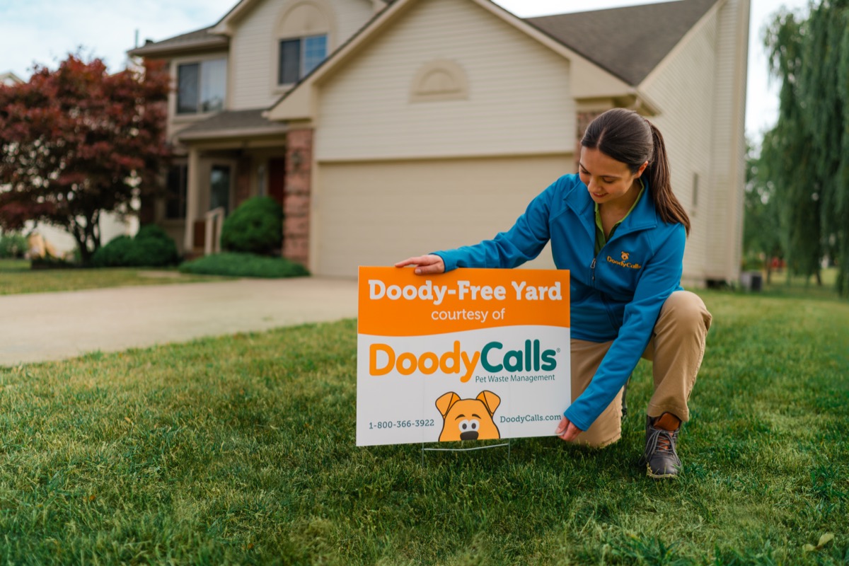 DoodyCalls technician placing a Doody-Free Yard sign