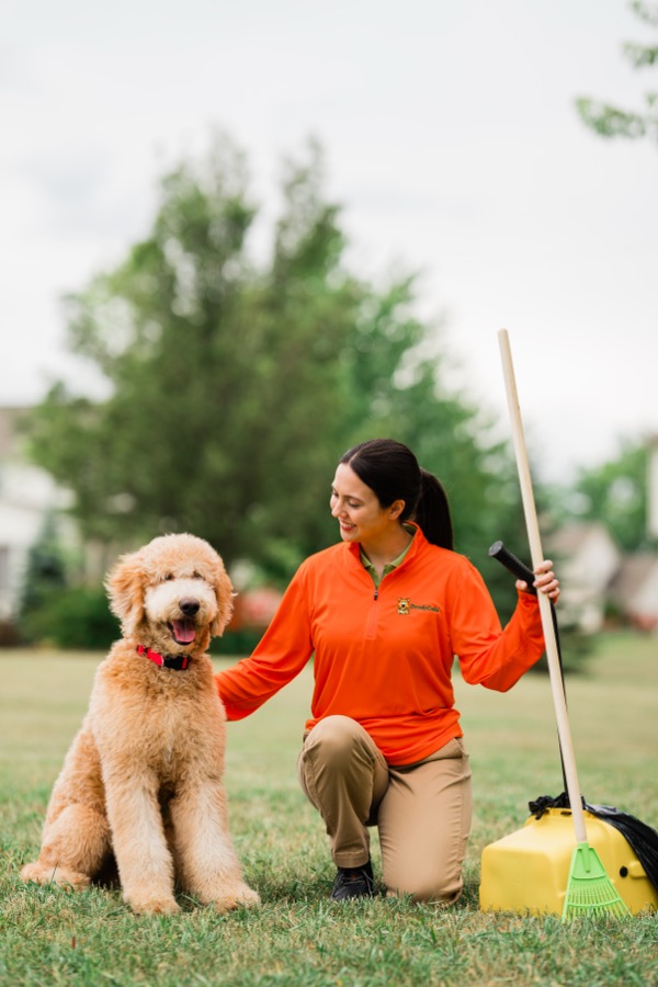 DoodyCalls technician kneeling with a happy dog