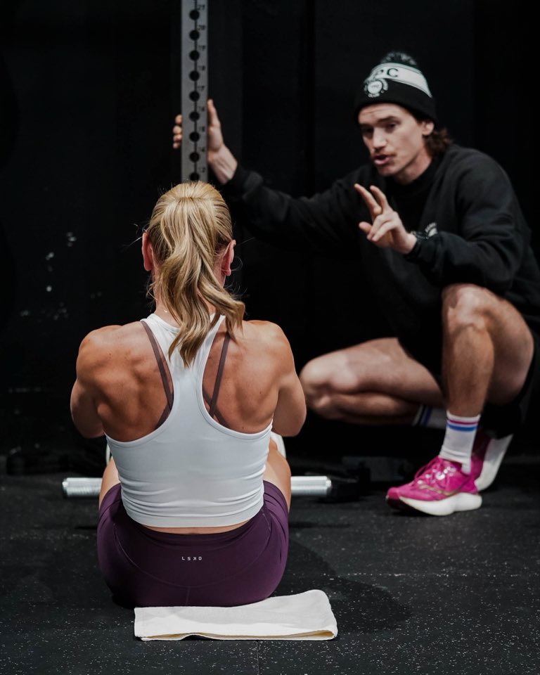 A coach crouched down explaining a movement to a member