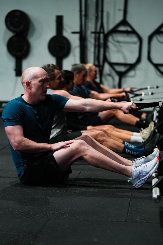A member rowing hard with four others in a line behind