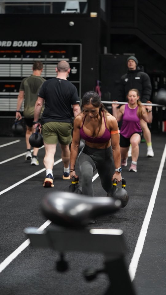 A member doing a kettlebell lunge on the track in a class at The Performance Club