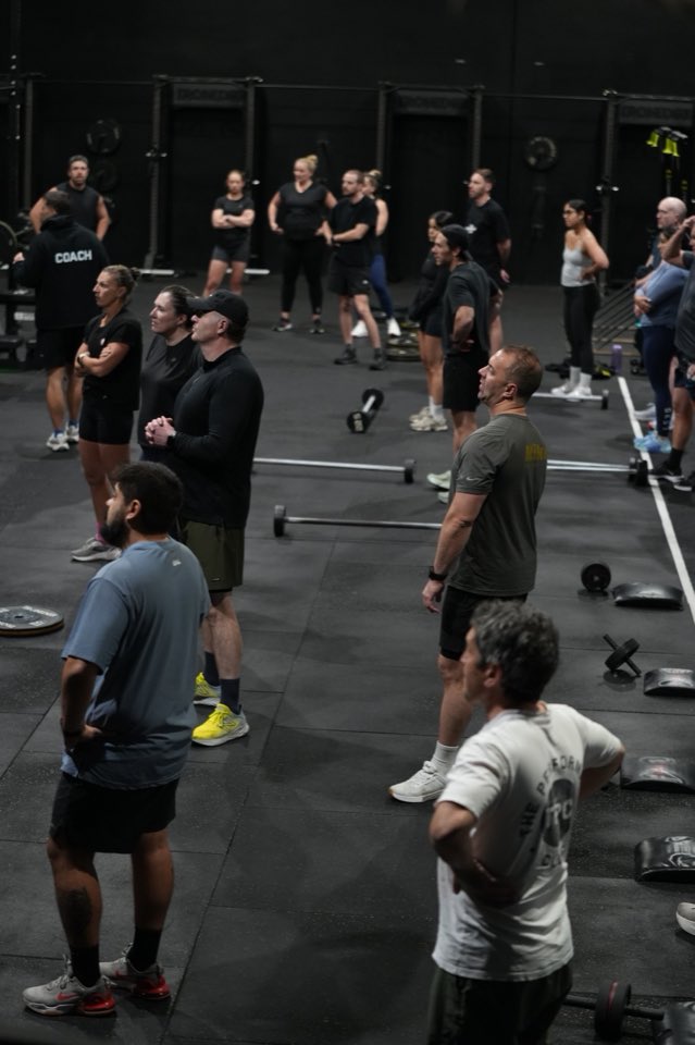 Members standing together listening to a coach before a workout