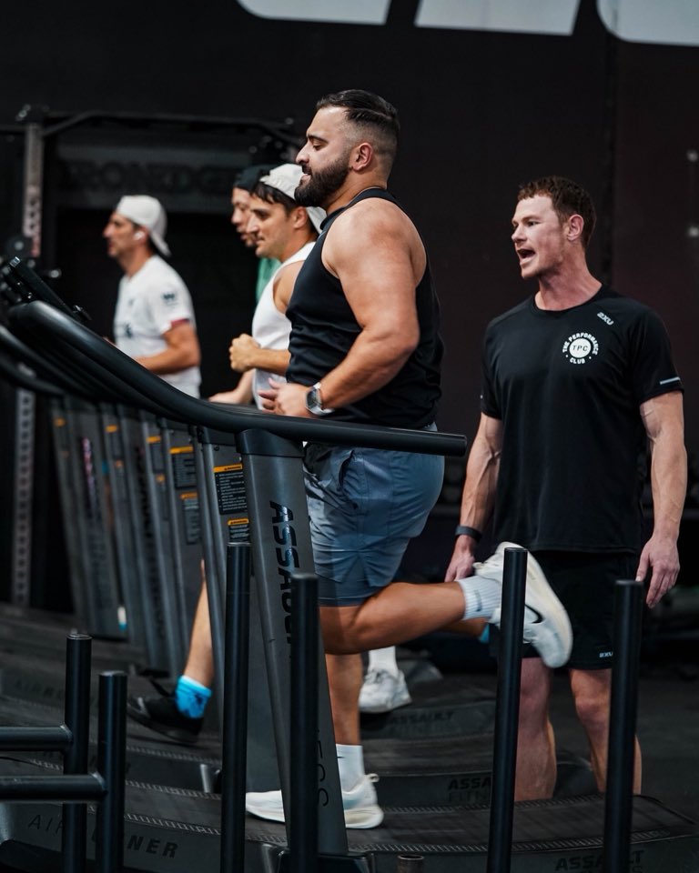 A coach cheering on a member running on the treadmill