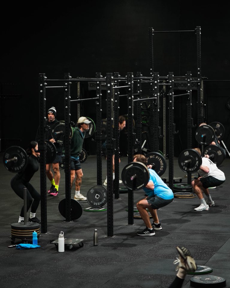 Six members back-squatting in the rig during a class