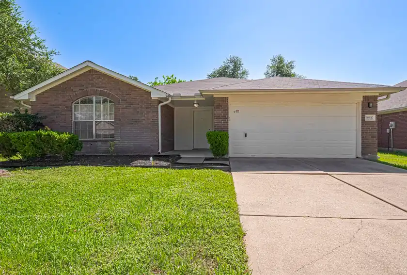A brick Houston-area house with a two-car garage, of the kind Charms Home Buyers purchases as-is