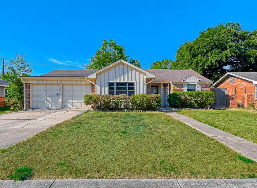 A single-storey Houston-area home with a mature lawn, hedges and a two-car garage