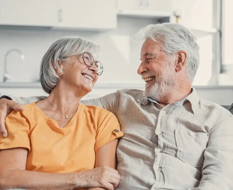 An older couple sitting together on the sofa in their Houston home, talking and smiling