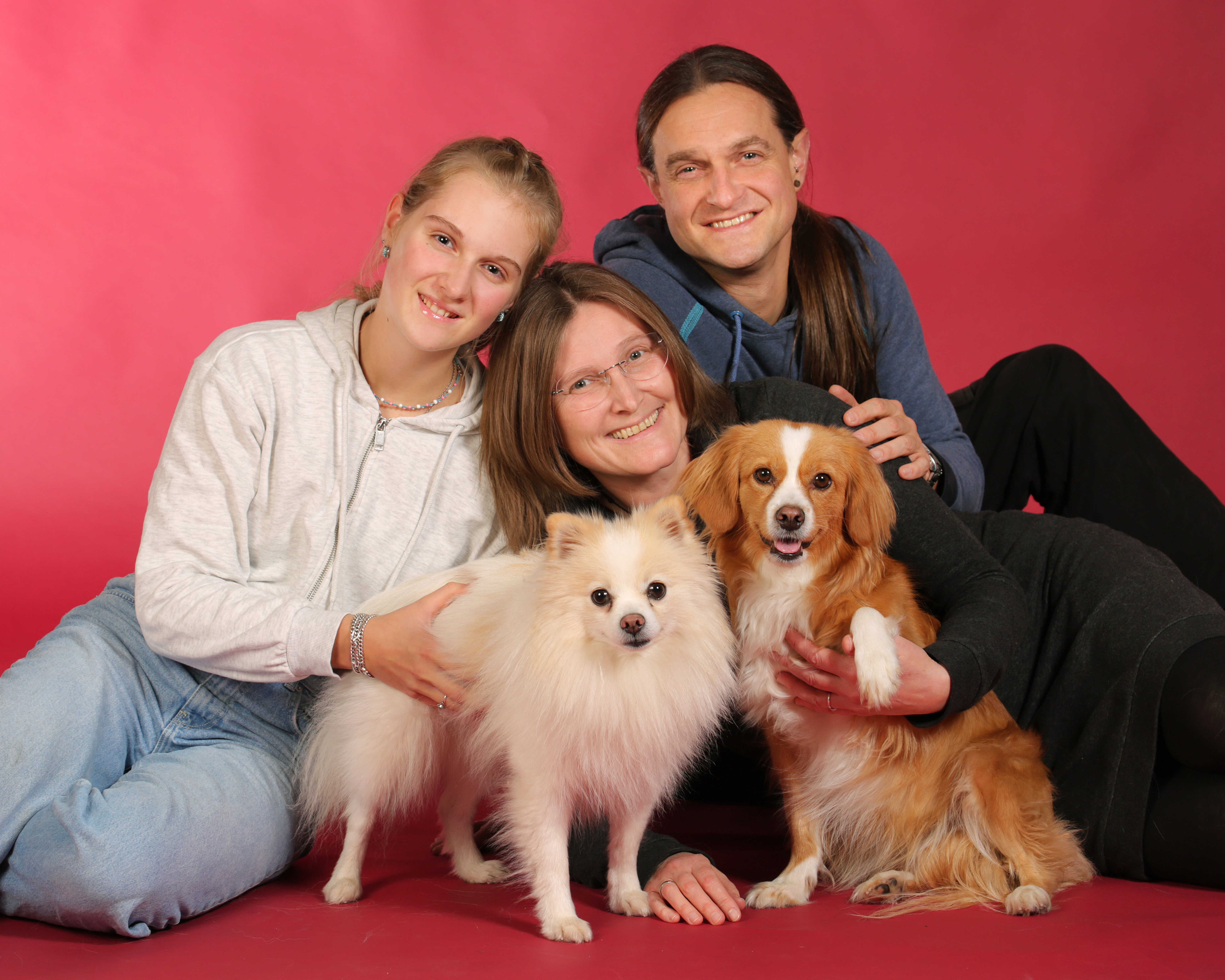 Familienporträt mit Hunden vor rotem weihnachtlichem Hintergrund