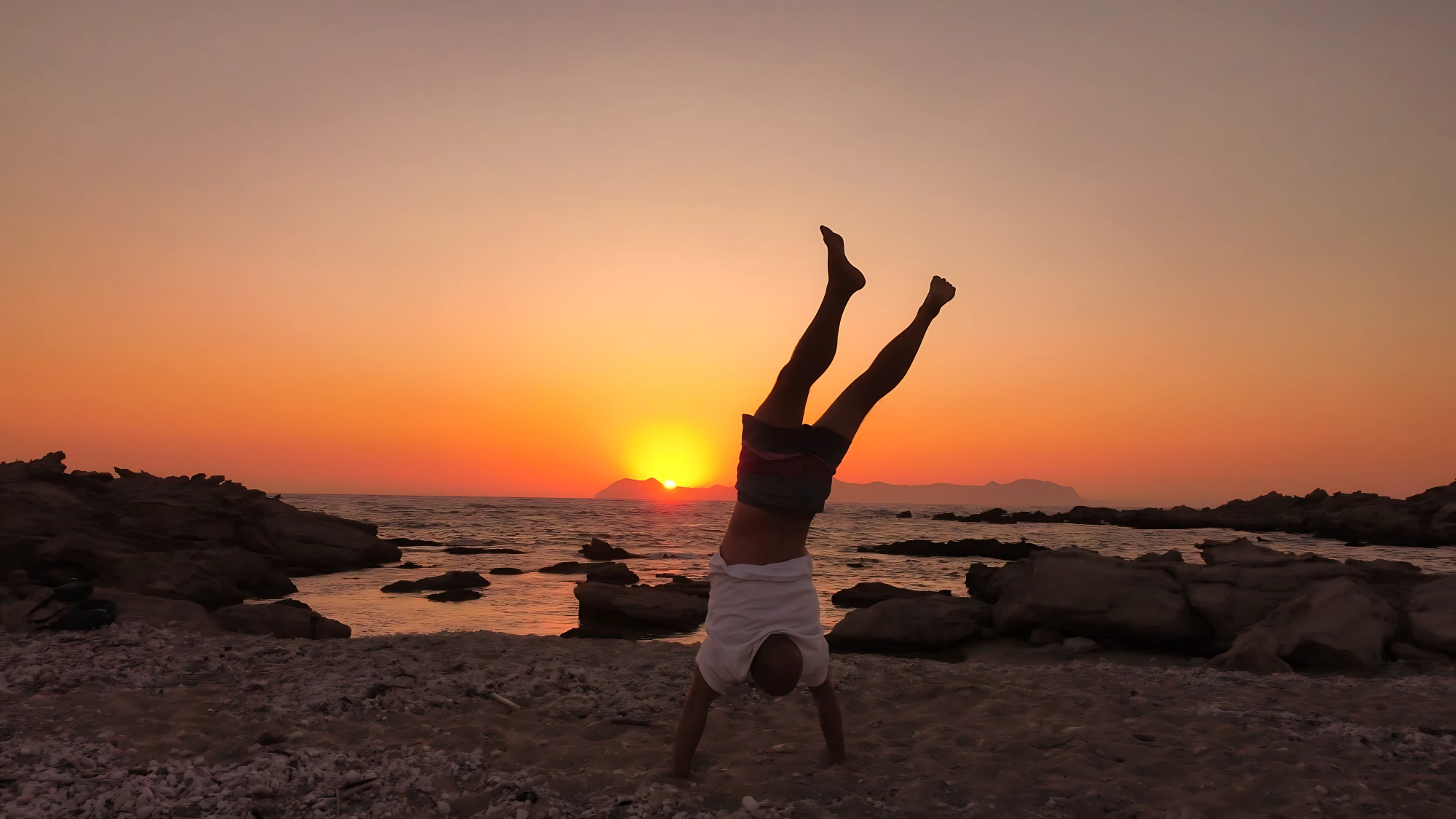 Ocean Wise host doing a handstand on deck at sunset