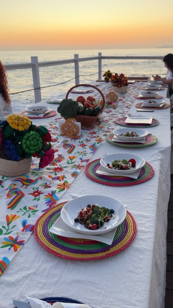 La mesa larga servida con ensaladas frente al mar al atardecer