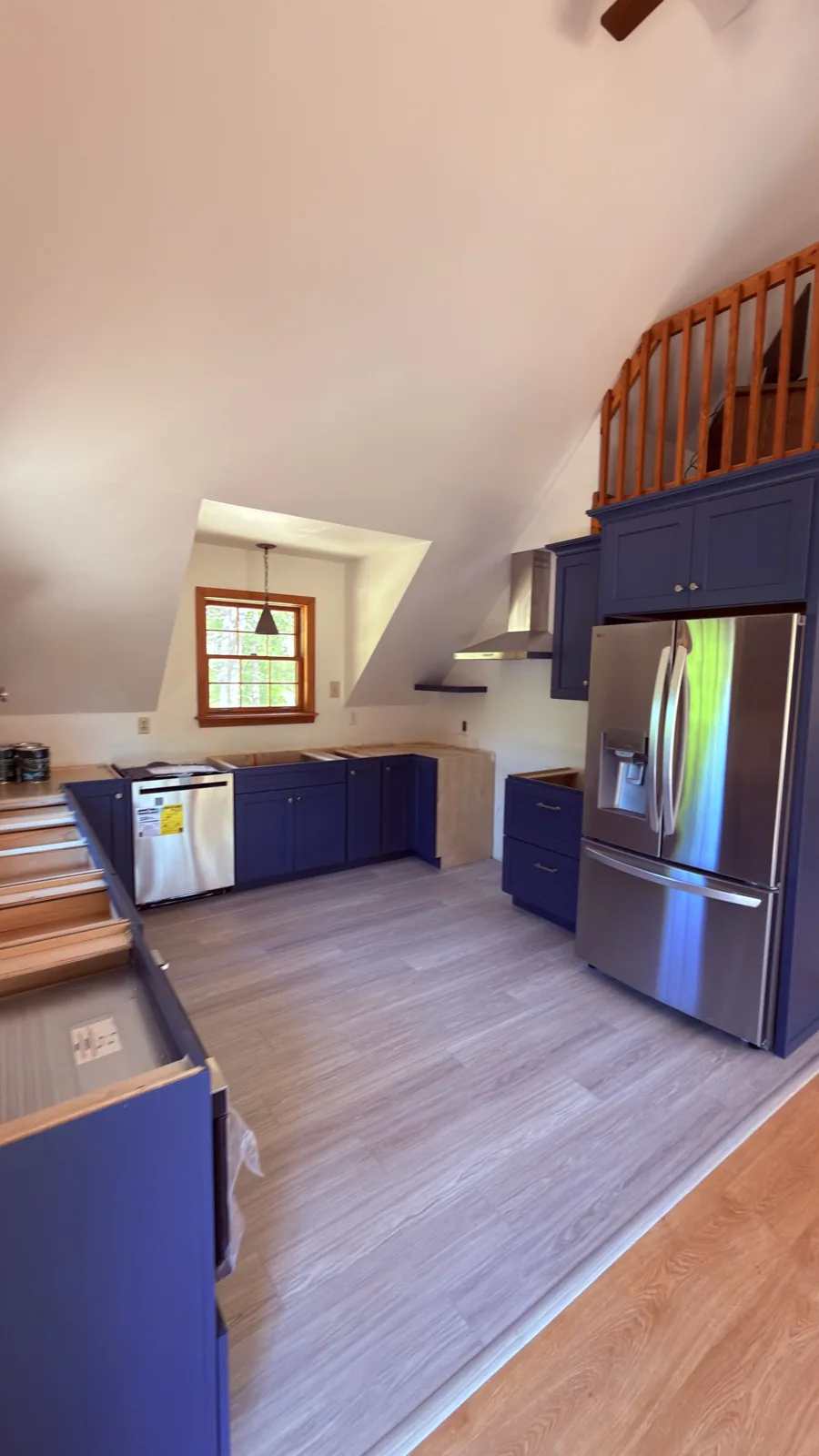 Navy kitchen cabinets with stainless appliances under a vaulted ceiling